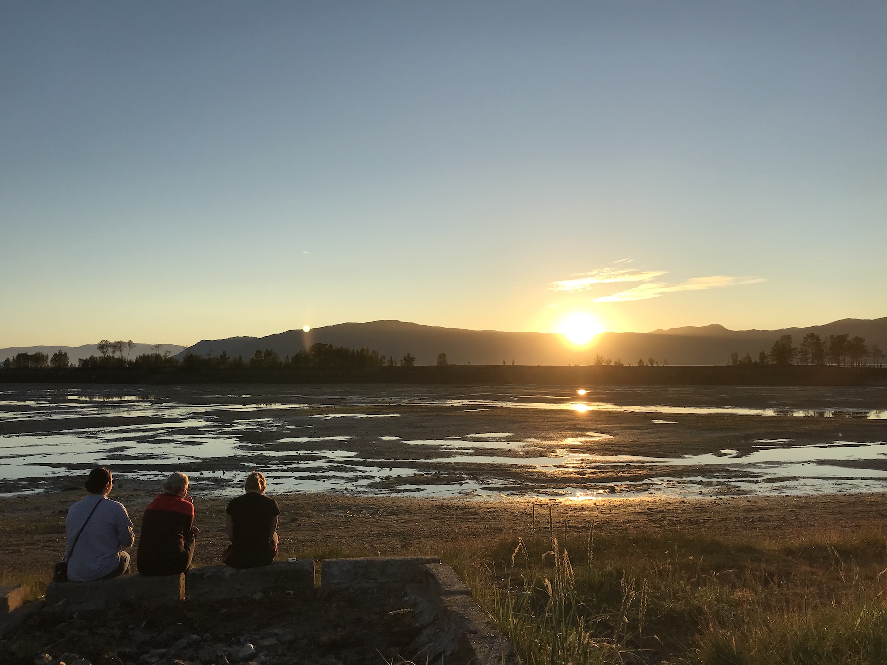 Midnight sun near the fjord in Norway during the low tide, high above the Arctic Circle, near Alta